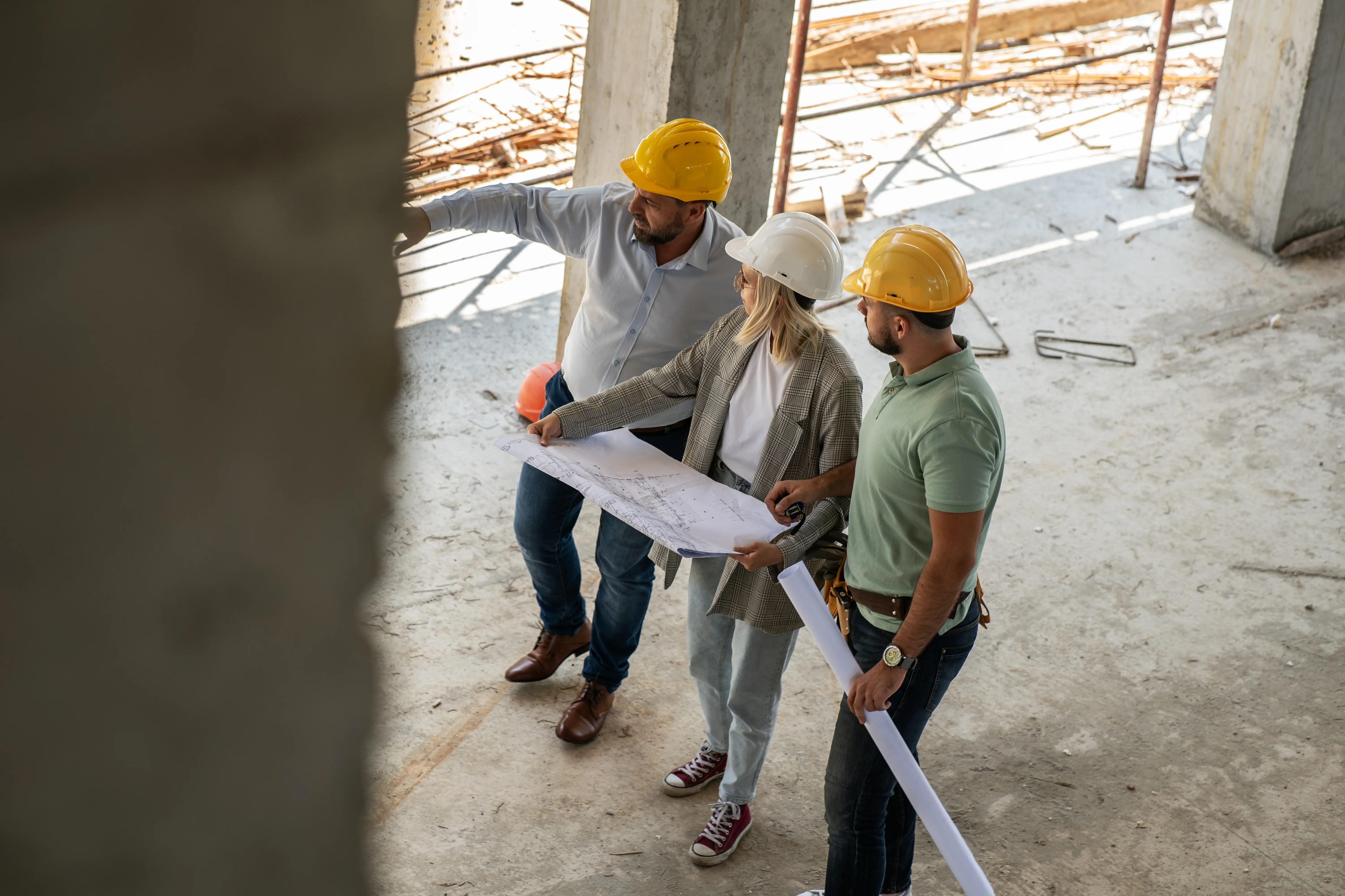 Three architects and construction manager discussing project details on job site.